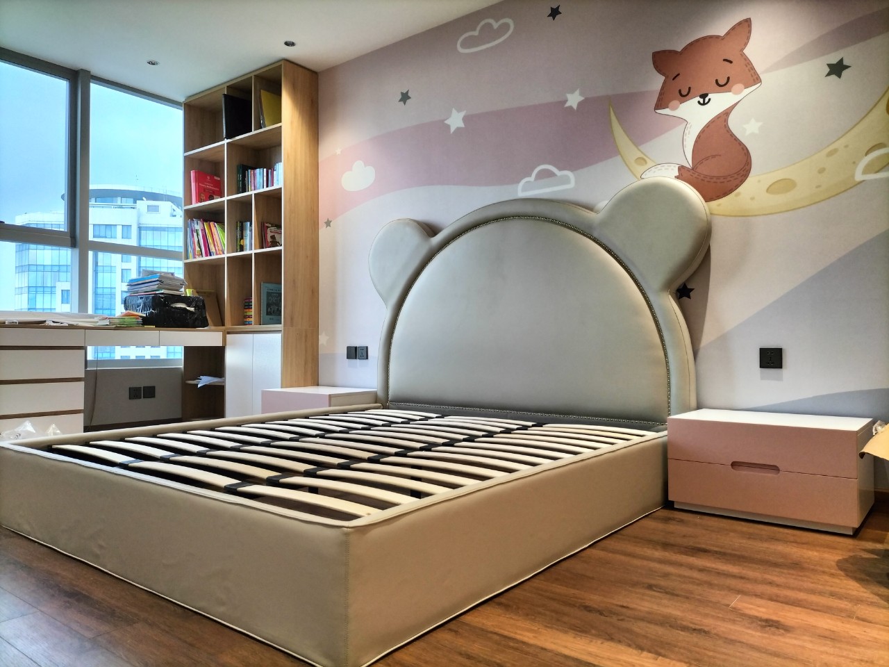 với những hình ảnh thú vui
Phòng ngủ trẻ em dành cho bé gái có một giường ngủ bọc da hình dáng con chuột, tab gỗ công nghiệp màu hồng và tranh dán tường với những hình ảnh thú vui.